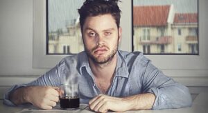 A man holding a cup of coffee with a scenario of coping with the aftermath of overindulgence, such as a hangover.