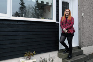 A woman standing on the steps of a house._SCALED