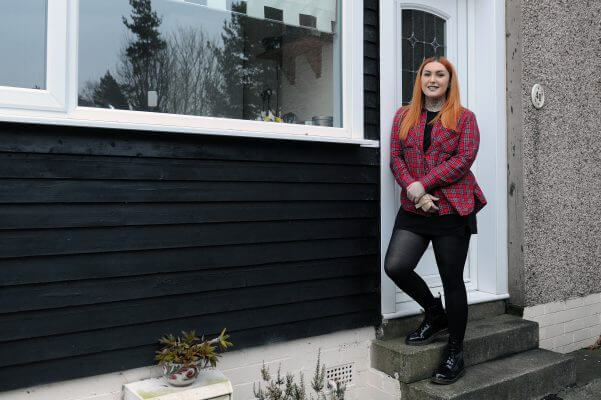 A woman standing on the steps of a house.