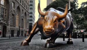 A statue of a bull on a cobblestone street.