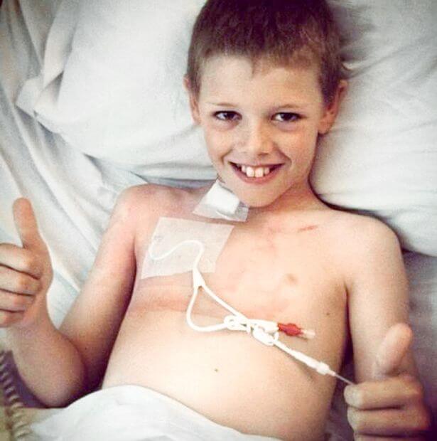 A brave boy battling cancer in a hospital bed, giving a thumbs up for the potential of cannabis as a treatment option.