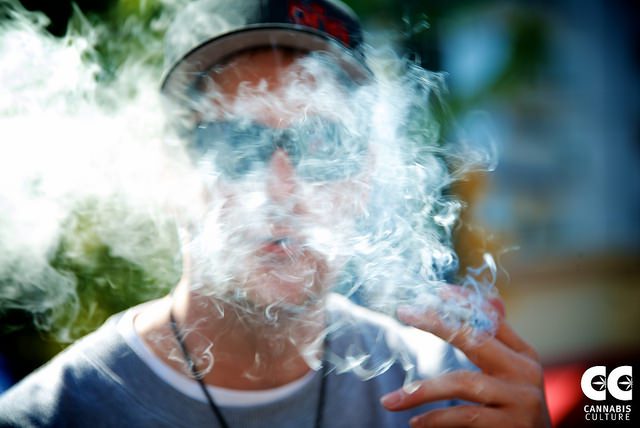 A man in sunglasses smokes a cigarette.