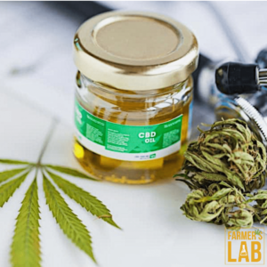  A jar of CBD oil, a pipette possibly used for dosing, a cannabis leaf, and some dried cannabis buds.